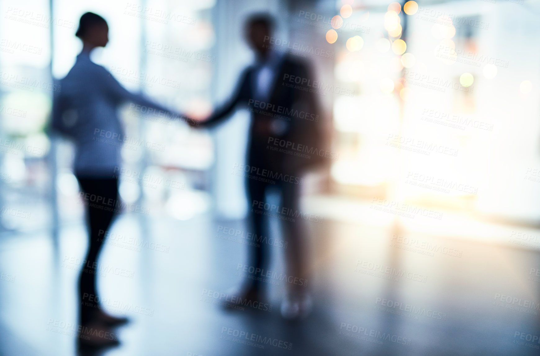 Buy stock photo Defocused shot of two businesspeople shaking hands in an office