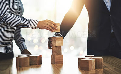 Buy stock photo Shot of two businesspeople stacking wooden blocks together in an office