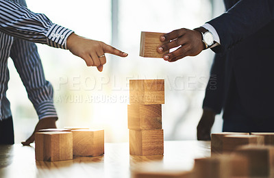 Buy stock photo Shot of two businesspeople stacking wooden blocks together in an office