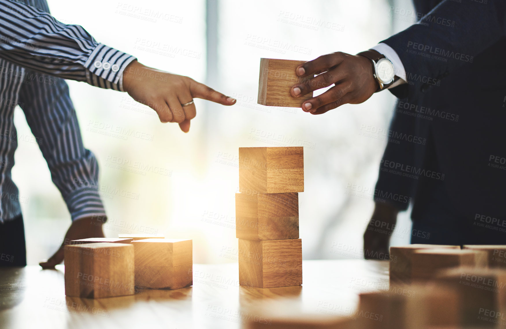 Buy stock photo Shot of two businesspeople stacking wooden blocks together in an office