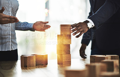 Buy stock photo Shot of two businesspeople stacking wooden blocks together in an office