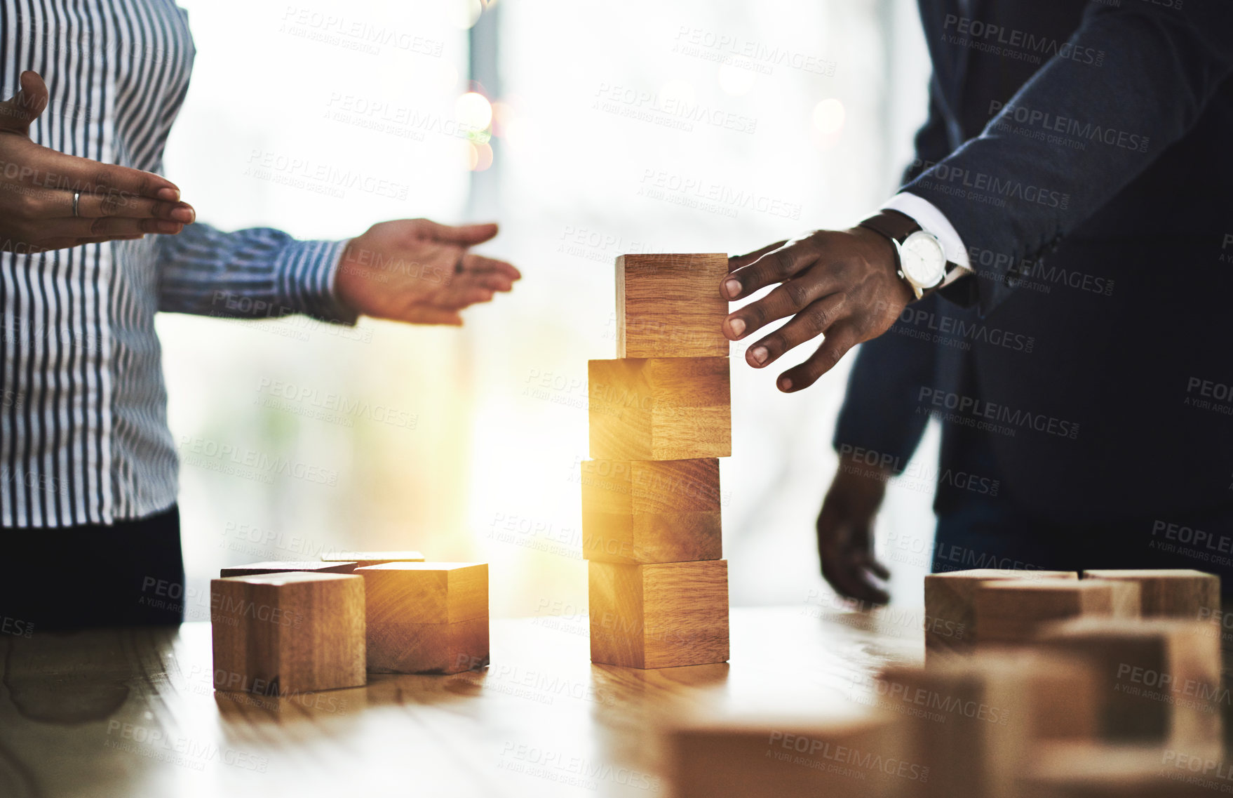 Buy stock photo Shot of two businesspeople stacking wooden blocks together in an office