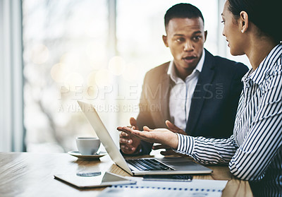 Buy stock photo Shot of two businesspeople working together on a laptop in an office