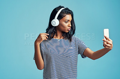 Buy stock photo Fashion, music and selfie of woman in studio for social media isolated on blue background. Photography, headphones and Indian girl in casual clothes or influencer listening to kpop on mockup space