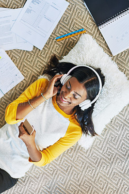 Buy stock photo High angle shot of a young female student listening to music while studying at home