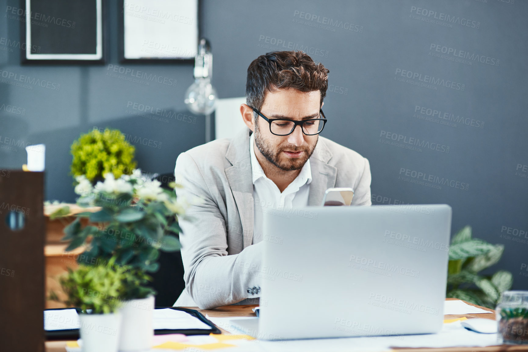 Buy stock photo Shot of a young businessman working on a laptop in an office