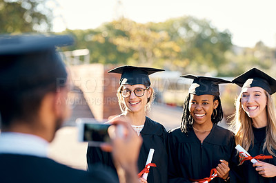 Buy stock photo People, photo and graduation outside with students, friends and smartphone for memory with education pride. Happy, smile and together with diploma achievement, university and capture in gown

