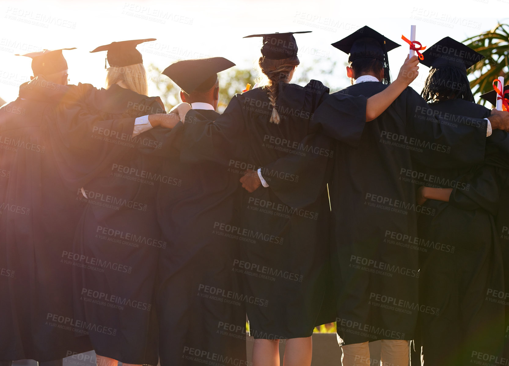 Buy stock photo Rearview shot of a group of university students standing together on graduation day