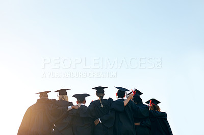 Buy stock photo Rearview shot of a group of university students standing together on graduation day