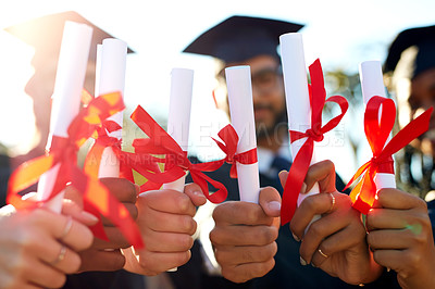 Buy stock photo Shot of a group of university students holding their diplomas together on graduation day