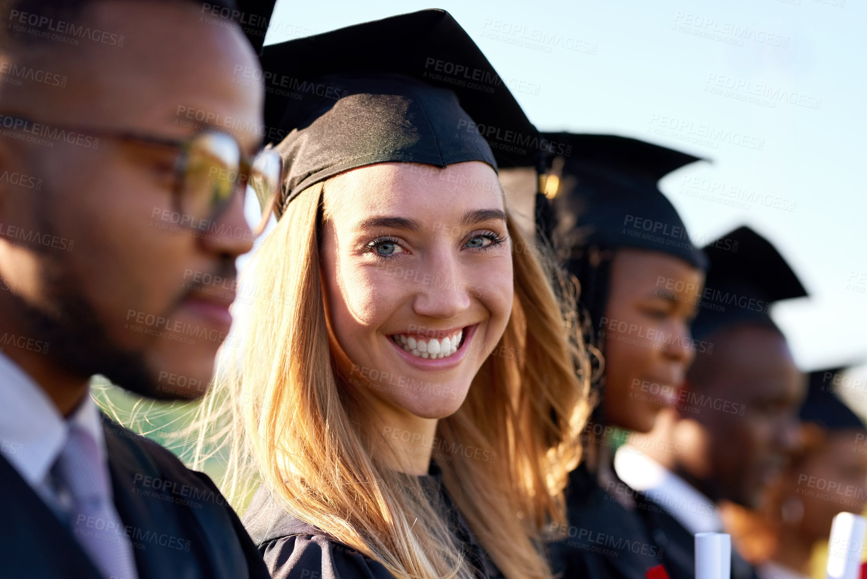 Buy stock photo Portrait of a university student standing amongst her classmates on graduation day