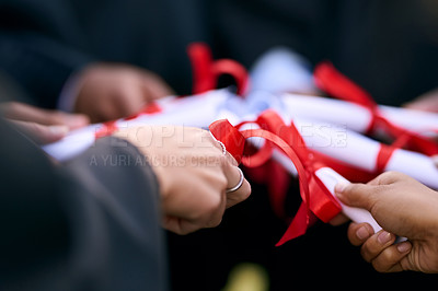Buy stock photo Closeup shot of a group of university students holding their diplomas together on graduation day