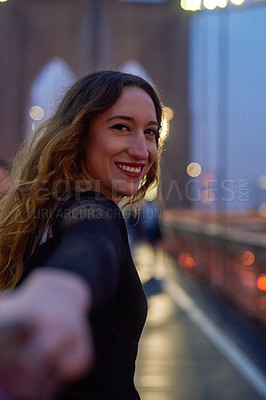 Buy stock photo Shot of a beautiful young woman leading her boyfriend by the hand in the city