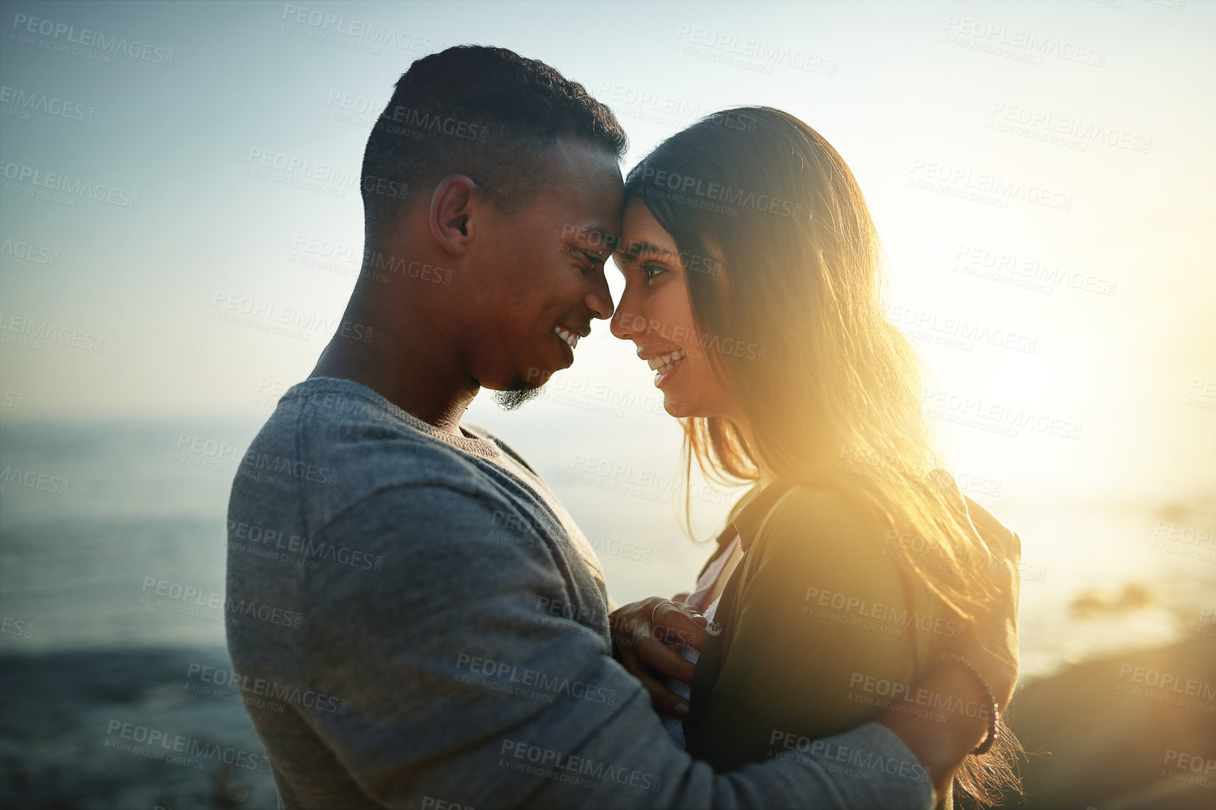 Buy stock photo Happy couple, hug and love with beach sunset for intimacy, embrace or holiday weekend together in nature. Young, man and woman with smile for bonding, romance or affection by ocean coast or sea