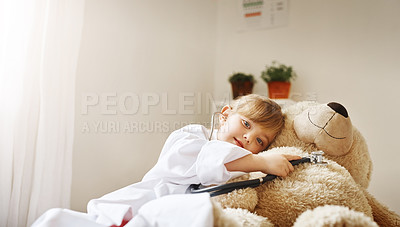 Buy stock photo Shot of an adorable little girl dressed up as a doctor and treating her teddy bear as a patient