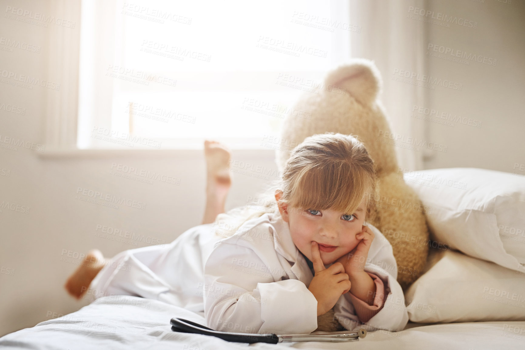 Buy stock photo Shot of an adorable little girl dressed up as a doctor and treating her teddy bear as a patient