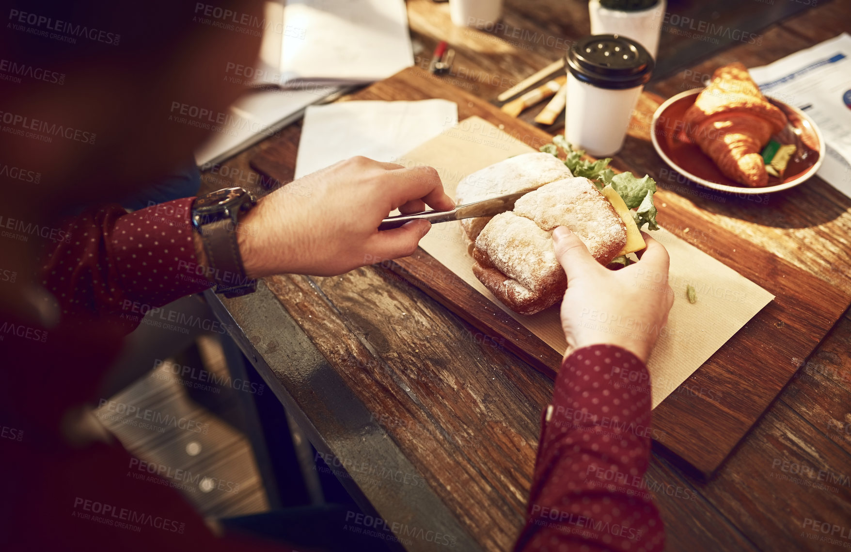 Buy stock photo Hands, breakfast and cut sandwich in restaurant with knife, coffee and table for eating, hungry and diet. Person, bread and slice food in cafe for lunch, nutrition and brunch with croissant and board