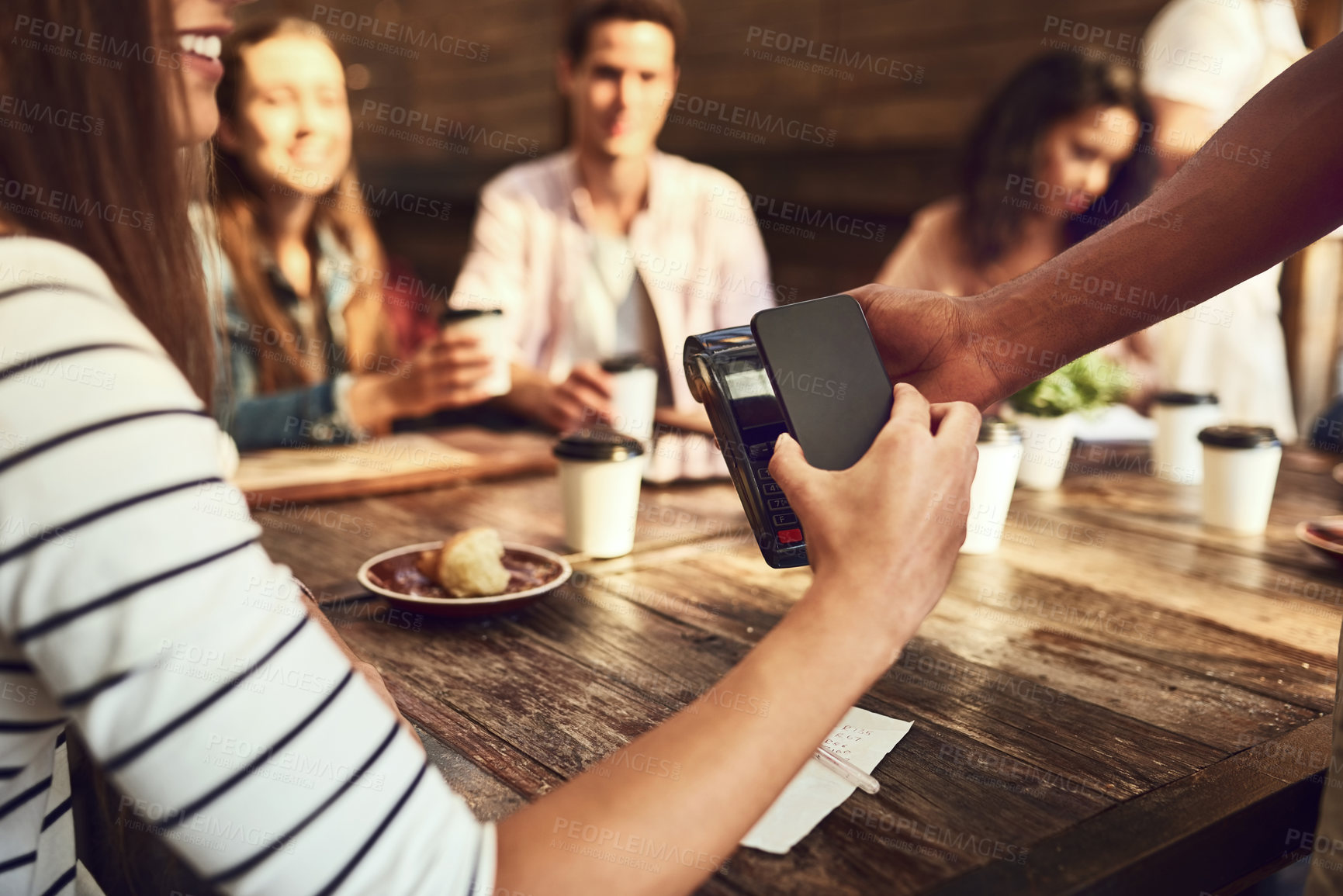 Buy stock photo Cropped shot of an unrecognizable woman paying with her phone at a cafe