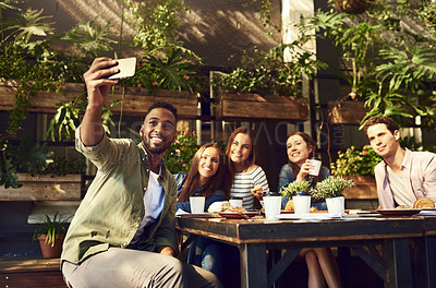 Buy stock photo Cropped shot of a handsome young man taking a selfie while out with friends at a cafe