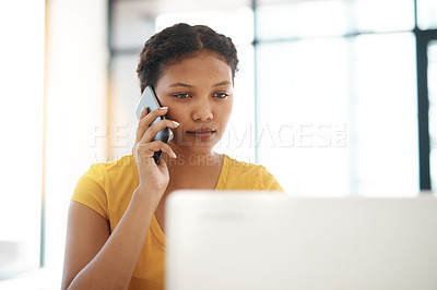 Buy stock photo Shot of a young businesswoman using a laptop and mobile phone at her desk in a modern office