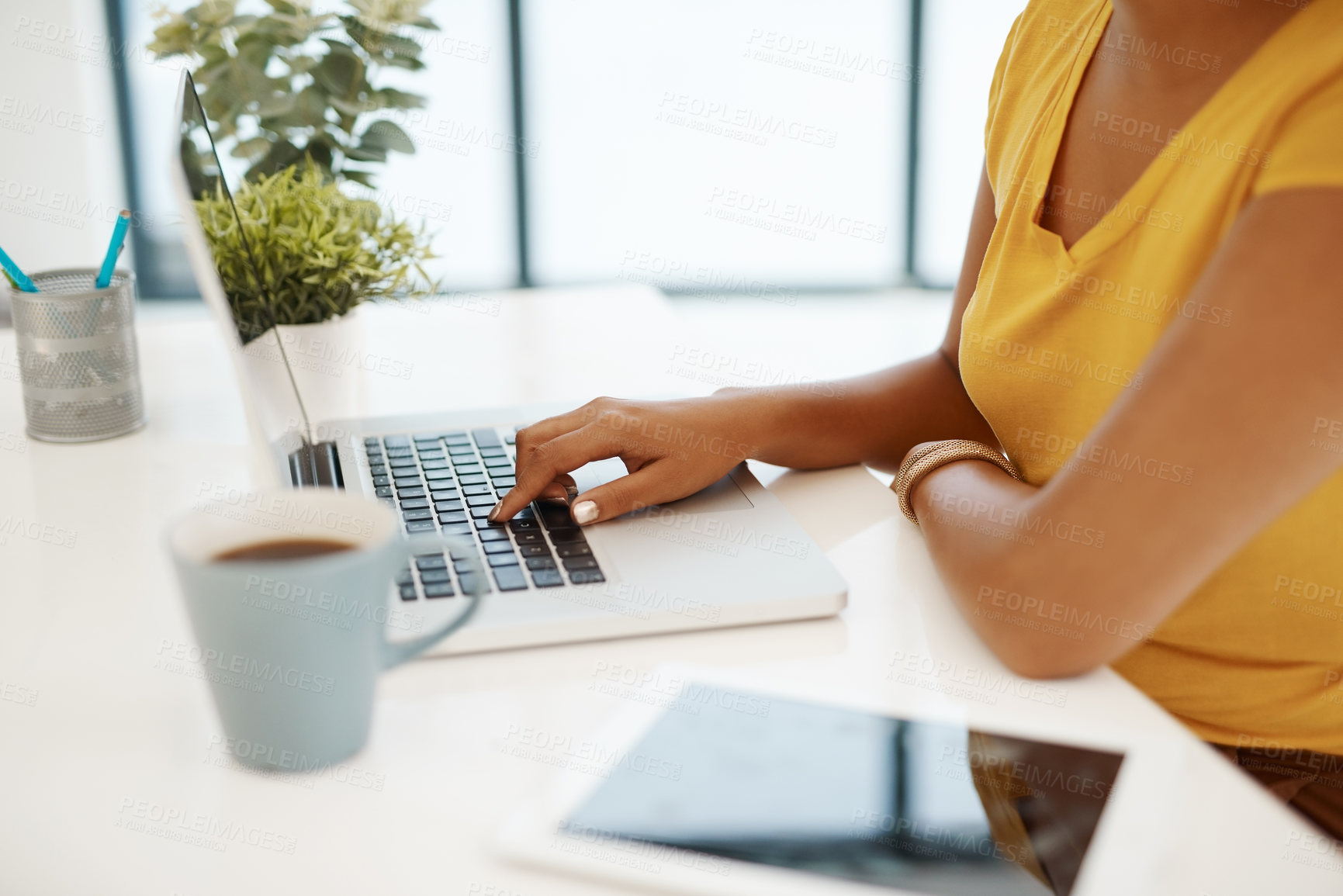 Buy stock photo Cropped shot of a businesswoman using a laptop at her desk in a modern office