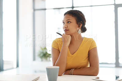 Buy stock photo Shot of a young businesswoman looking thoughtful at her desk in a modern office