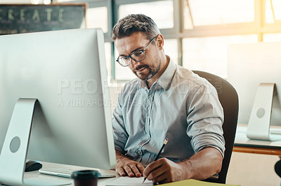 Buy stock photo Shot of a mature businessman using a computer in a modern office