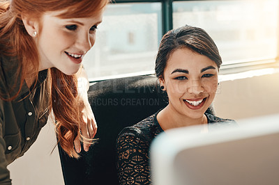 Buy stock photo Shot of two young businesswomen using a computer together in a modern office