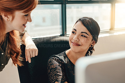 Buy stock photo Shot of two young businesswomen using a computer together in a modern office