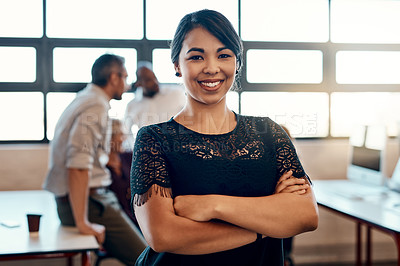 Buy stock photo Portrait of a confident young businesswoman standing in a modern office with her colleagues in the background