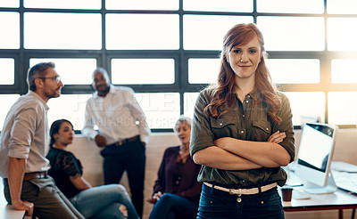 Buy stock photo Portrait of a confident young businesswoman standing in a modern office with her colleagues in the background
