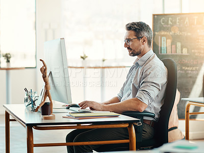 Buy stock photo Shot of a mature businessman using a computer in a modern office