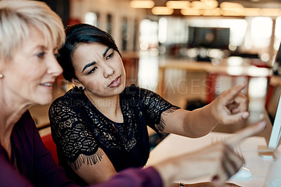 Buy stock photo Shot of two businesswomen using a computer together in a modern office