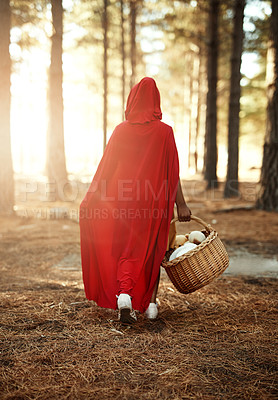 Buy stock photo Rear view shot of a little girl in a red cape walking in the woods with a basket