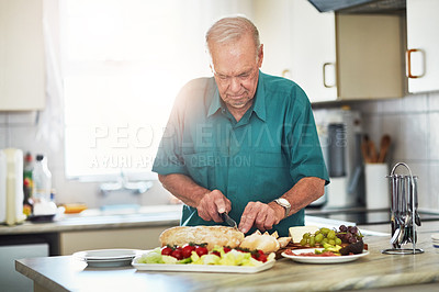 Buy stock photo Cropped shot of a senior man making lunch in his kitchen at home