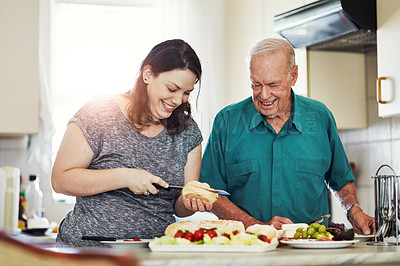 Buy stock photo Cropped shot of a woman making her senior male parent a sandwich