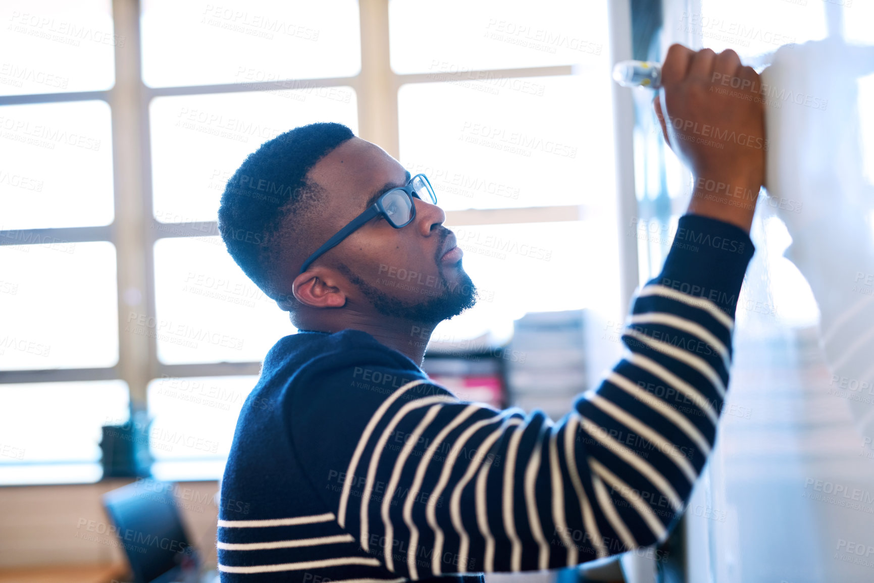 Buy stock photo Cropped shot of a young man writing on a whiteboard in a classroom