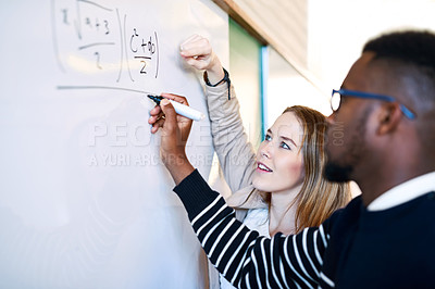 Buy stock photo Shot of a young man writing on a whiteboard while students look on