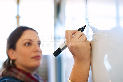 Buy stock photo Cropped shot of a young woman writing on a whiteboard in a classroom
