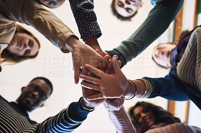 Buy stock photo Low angle portrait of a group of young friends standing with their hands in a huddle