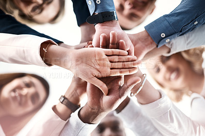 Buy stock photo Low angle portrait of a group of businesspeople putting their hands together in a huddle