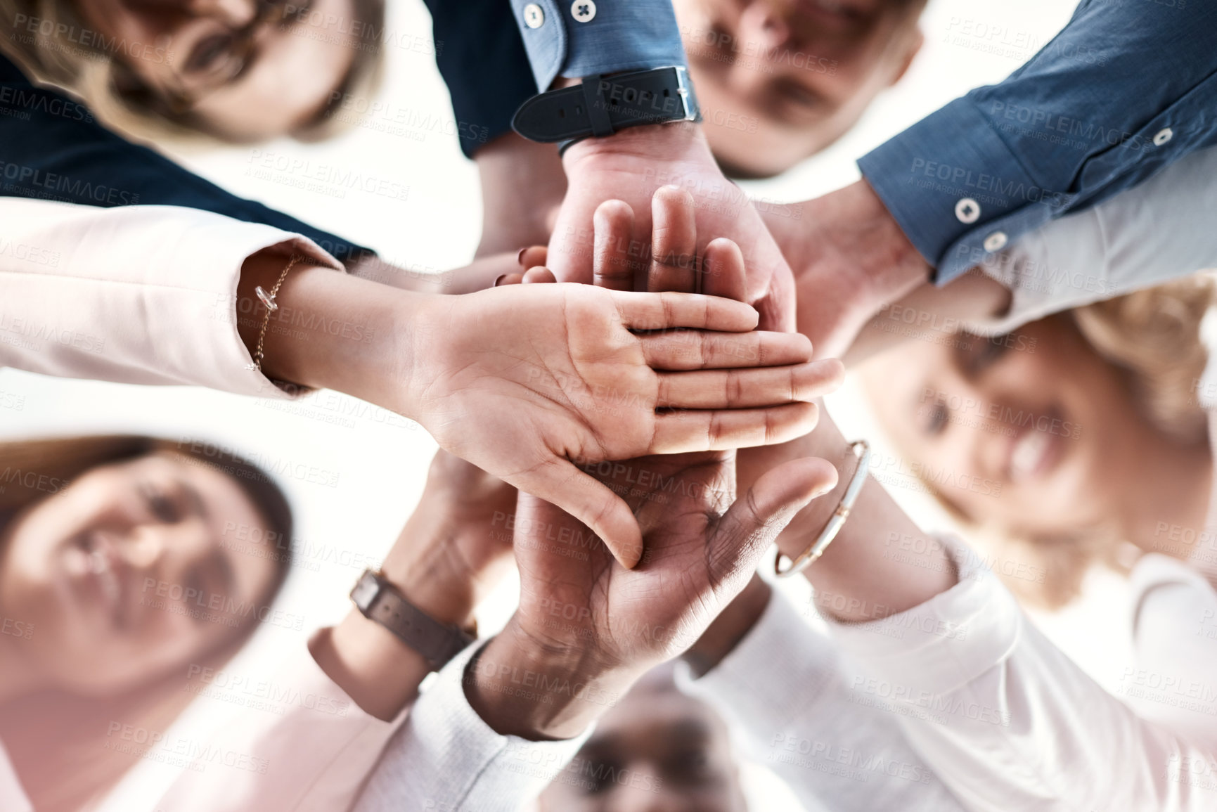 Buy stock photo Low angle portrait of a group of businesspeople putting their hands together in a huddle