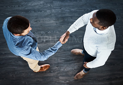 Buy stock photo High angle shot of two businessmen shaking hands while standing in an office