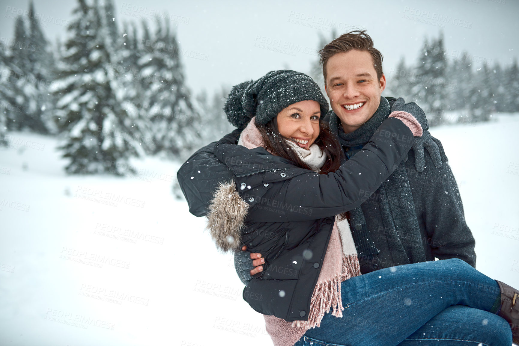Buy stock photo Shot of a happy young couple enjoying themselves while being out in the snow