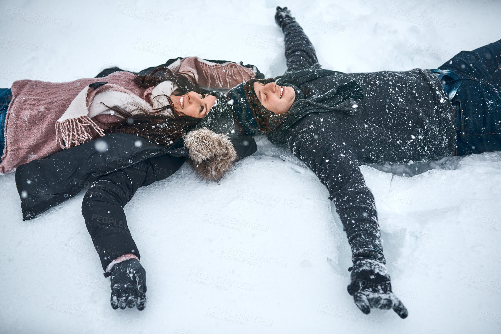 Buy stock photo High angle shot of a couple lying in the snow making snow angels