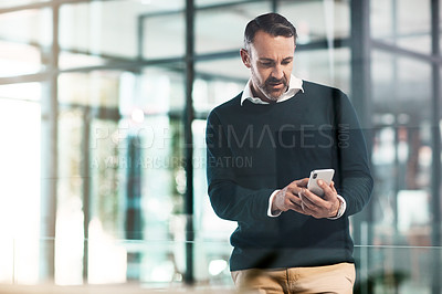 Buy stock photo Shot of a mature businessman using a mobile phone in a modern office