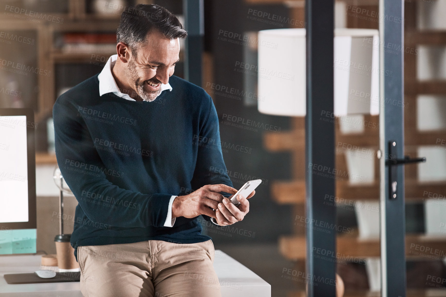 Buy stock photo Shot of a mature businessman using a mobile phone in a modern office