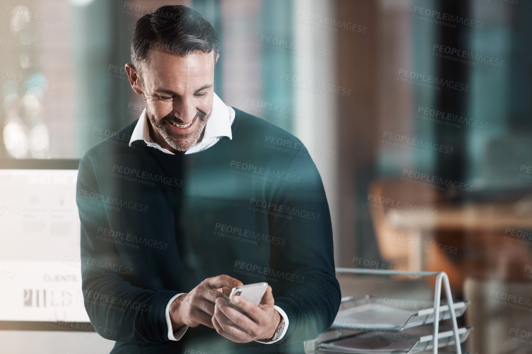 Buy stock photo Shot of a mature businessman using a mobile phone in a modern office