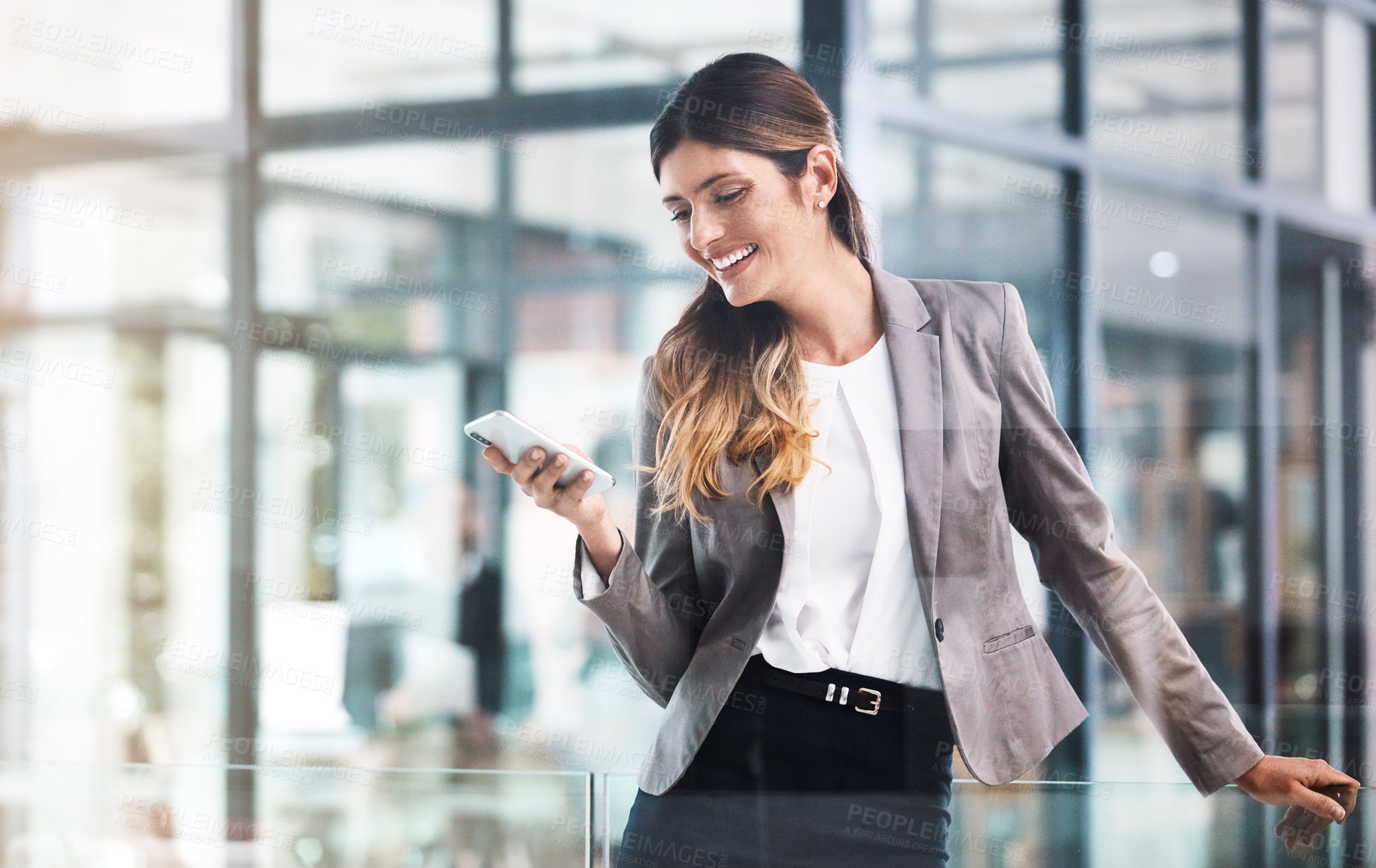 Buy stock photo Shot of a young businesswoman using a mobile phone in a modern office