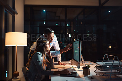Buy stock photo Shot of a businessman and businesswoman using a computer during a late night at work